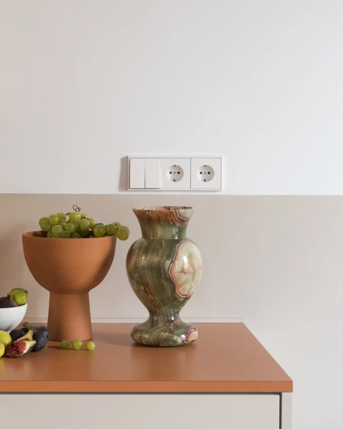 Jung switch and double socket range on a wall above a styled terracotta countertop